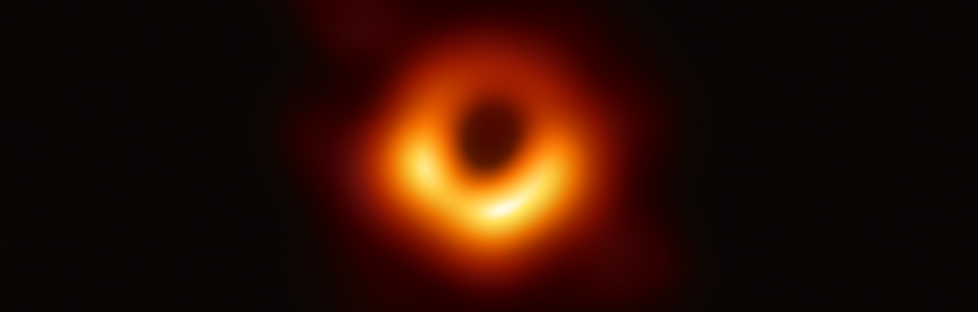 Black hole at M87*; a red/orange circle, thicker at the bottom with a black center; the entire circle is on a black background